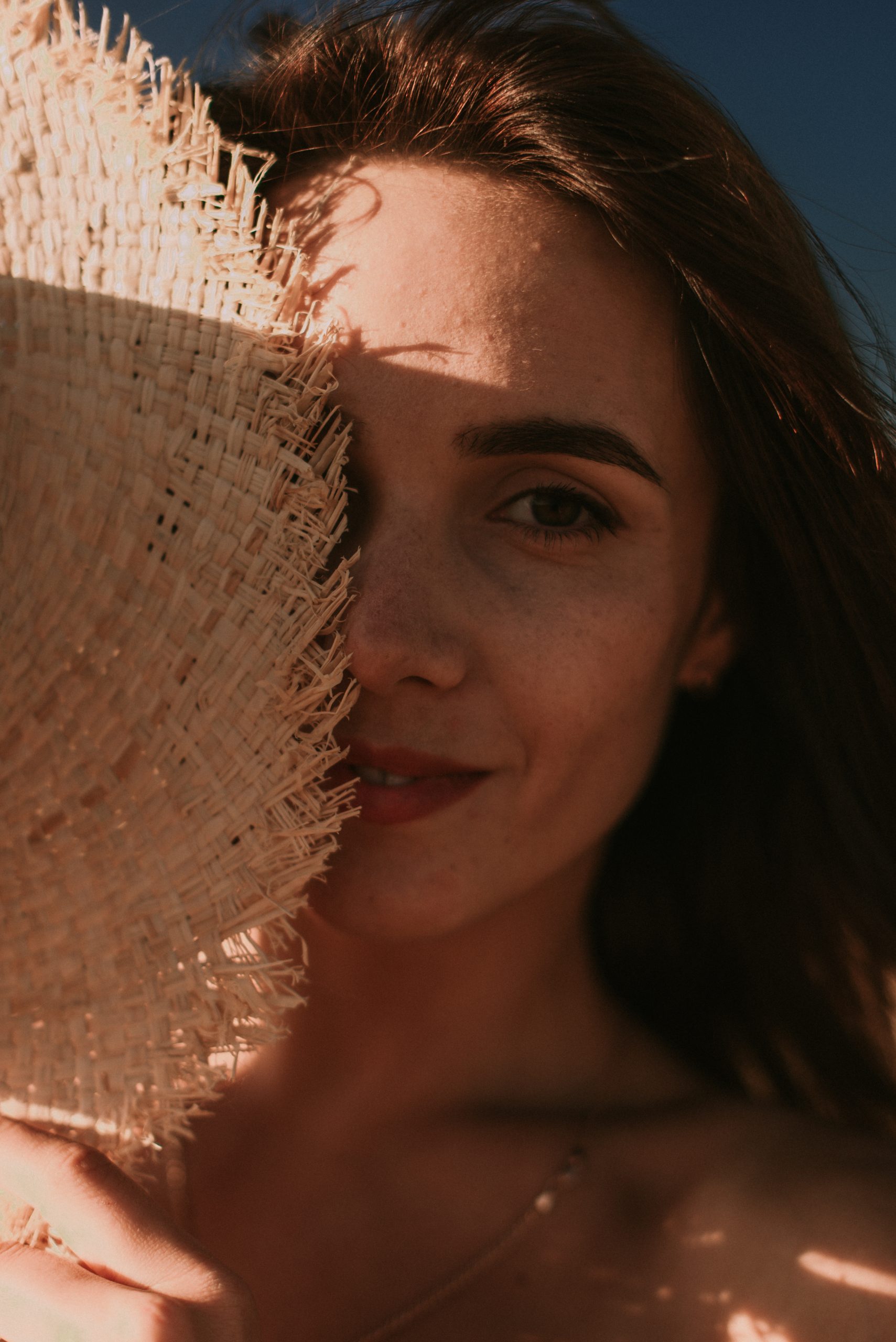 Portrait of a young woman holding hat in summer field